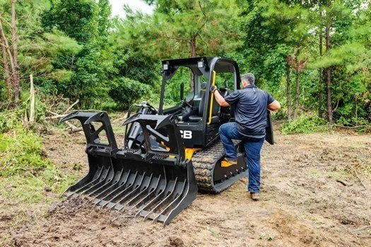 Man climbing on a small crawler skid steer loader